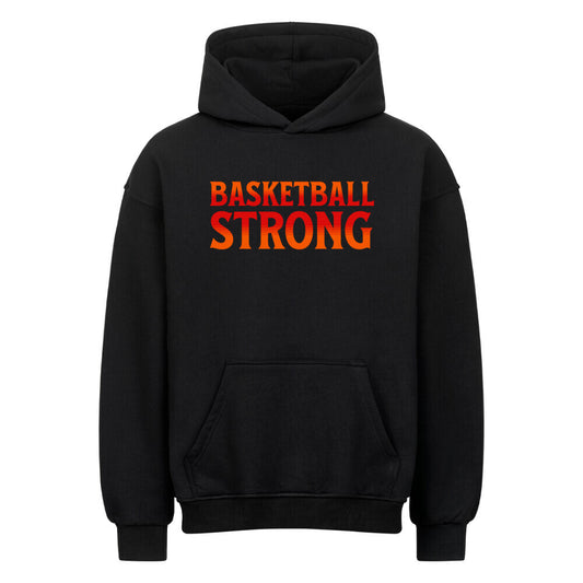 Vorderansicht eines schwarzen Oversized-Hoodies mit dem Aufdruck 'BASKETBALL STRONG' in einer rot-orangen Farbverlaufsschrift auf der Brust. 80% Baumwolle 20% Polyester.