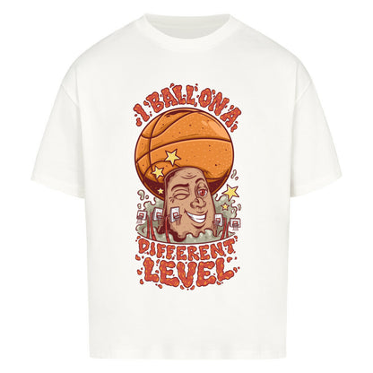 Weißes Oversized Basketball T-Shirt mit einem bunten Cartoon-Print einer zwinkernden Figur, die einen Basketball als Kopf hat. Der rote Text lautet „I BALL ON A DIFFERENT LEVEL“. 100% Baumwolle