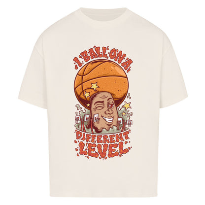 Natural Raw Oversized Basketball T-Shirt mit einem bunten Cartoon-Print einer zwinkernden Figur, die einen Basketball als Kopf hat. Der rote Text lautet „I BALL ON A DIFFERENT LEVEL“. 100% Baumwolle