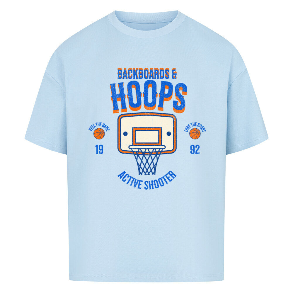 Babyblaues Oversized T-Shirt mit Retro-Print eines Basketballkorbs, dem Text „BACKBOARDS & HOOPS“ und dem Geburtsjahr „19 92“ in Orange und Blau. 100% Baumwolle