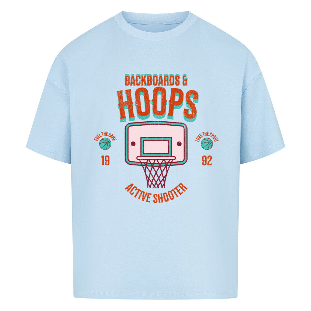 Babyblaues Oversized T-Shirt mit 90er-Jahre-Retro-Print eines Basketballkorbs und den Schriftzügen „BACKBOARDS & HOOPS“, „ACTIVE SHOOTER“ und „19 92“ in Orange und Türkis. 100% Baumwolle.