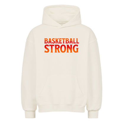Vorderansicht eines cremefarbenen Oversized-Hoodies mit dem Aufdruck 'BASKETBALL STRONG' in einer rot-orangen Farbverlaufsschrift auf der Brust. 80% Baumwolle 20% Polyester.