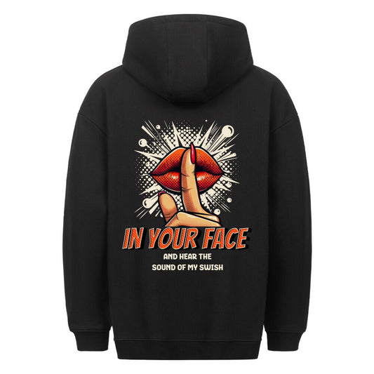 Rückansicht eines schwarzen Oversized-Hoodies mit Pop-Art-Print von roten Lippen und einem 'Shh'-Finger, mit dem Spruch 'IN YOUR FACE AND HEAR THE SOUND OF MY SWISH'. 80% Baumwolle 20% Polyester.