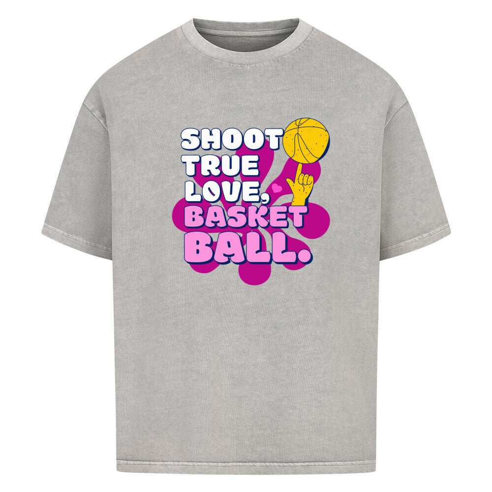 Washed Grey Oversized T-Shirt aus 100% Baumwolle mit einem pink-lila Retro-Print. Der Text lautet "SHOOT TRUE, LOVE, BASKETBALL" in Weiß mit dicken Rändern. Das Motiv zeigt einen Basketball und eine Hand.
