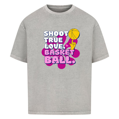 Washed Grey Oversized T-Shirt aus 100% Baumwolle mit einem pink-lila Retro-Print. Der Text lautet "SHOOT TRUE, LOVE, BASKETBALL" in Weiß mit dicken Rändern. Das Motiv zeigt einen Basketball und eine Hand.