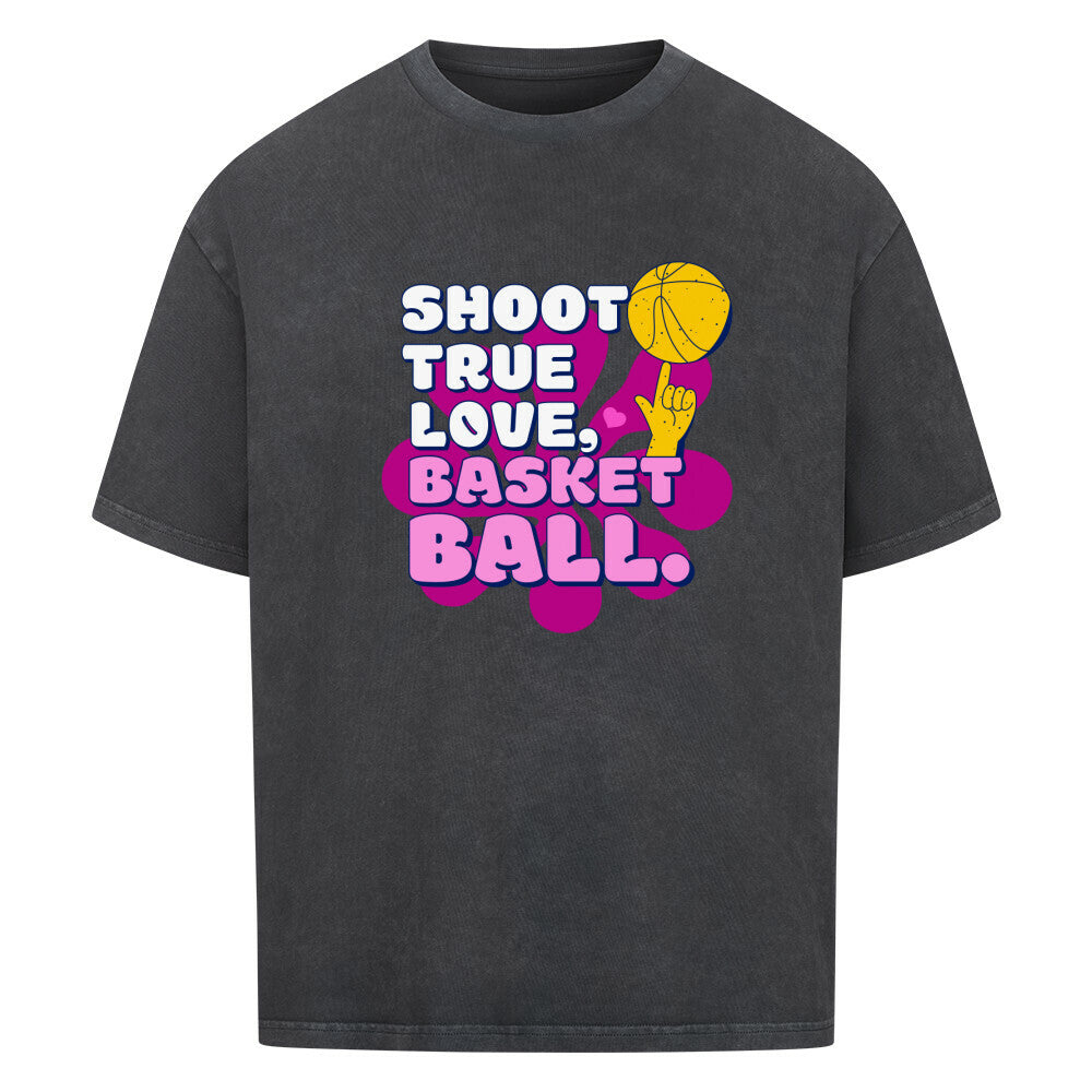 Washed Schwarz Oversized T-Shirt aus 100% Baumwolle mit einem pink-lila Retro-Print. Der Text lautet "SHOOT TRUE, LOVE, BASKETBALL" in Weiß mit dicken Rändern. Das Motiv zeigt einen Basketball und eine Hand.