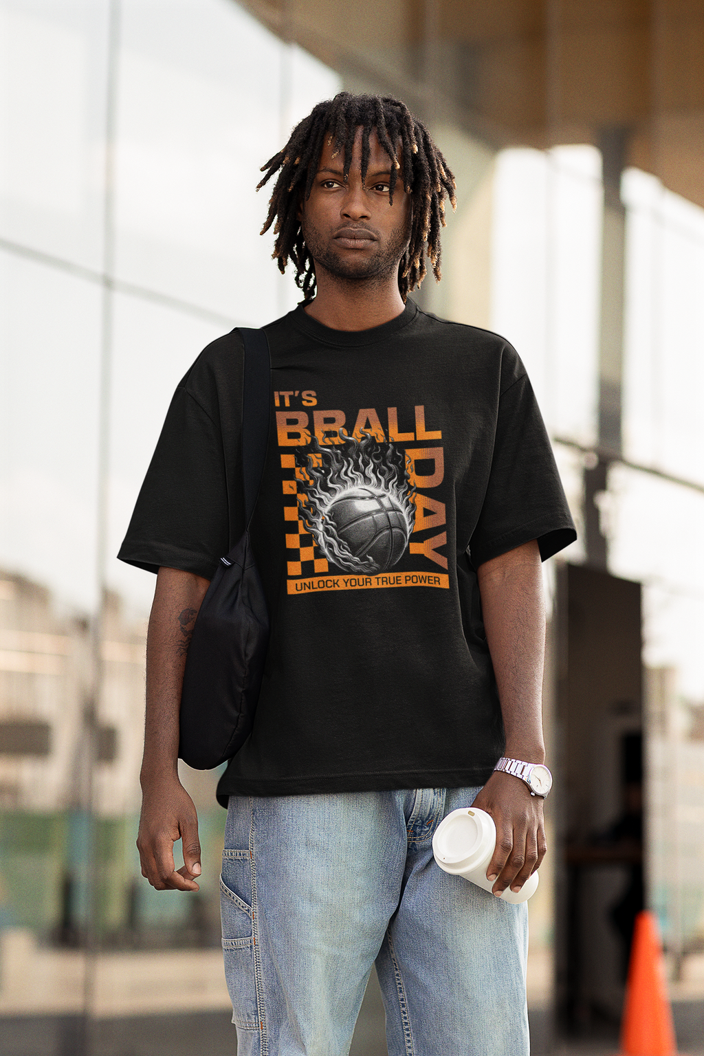 Mockup mit Model Schwarzes Oversized T-Shirt mit einem Print eines brennenden Basketballs (Ball on Fire) und dem orangefarbenen Text „IT'S BBALL DAY“ und „UNLOCK YOUR TRUE POWER“. 100% Baumwolle.