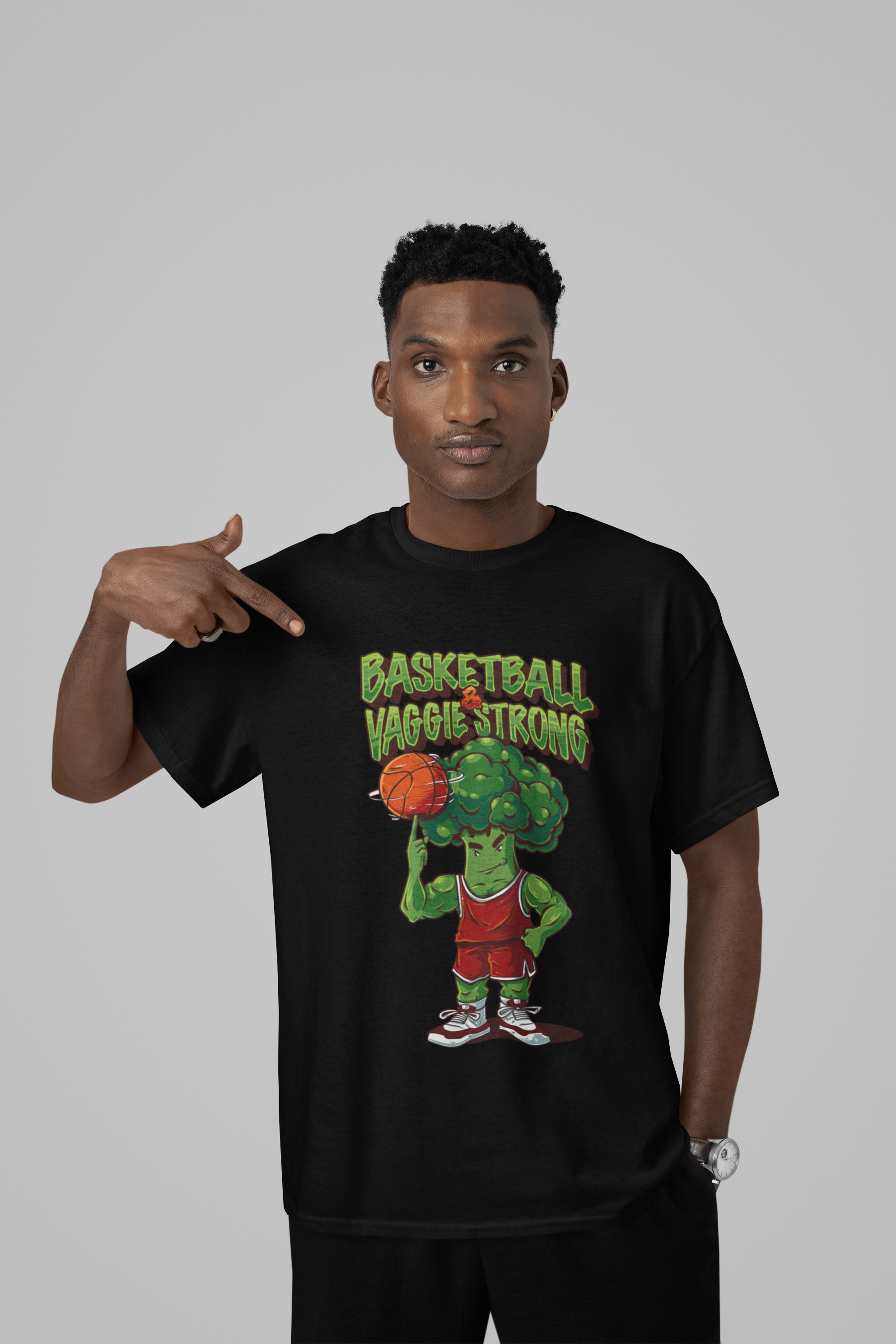 Mockup mit Model Schwarzes Oversized T-Shirt mit Print: Ein muskulöser Brokkoli im Basketball-Trikot spielt Basketball, darüber der grüne Schriftzug "BASKETBALL VAGGIE STRONG". 100% Baumwolle.