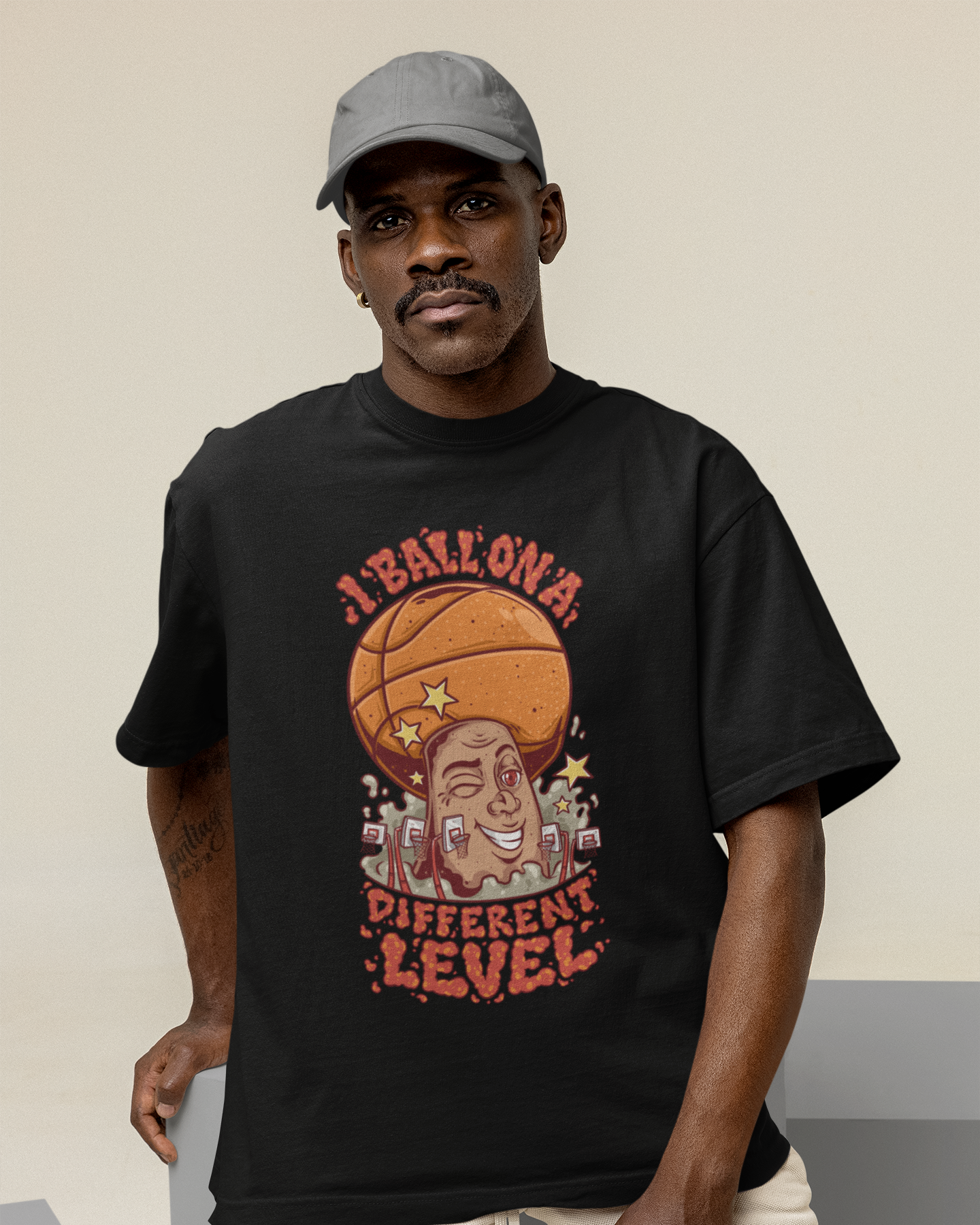 Mockup mit Model Schwarzes Oversized Basketball T-Shirt mit einem bunten Cartoon-Print einer zwinkernden Figur, die einen Basketball als Kopf hat. Der rote Text lautet „I BALL ON A DIFFERENT LEVEL“. 100% Baumwolle
