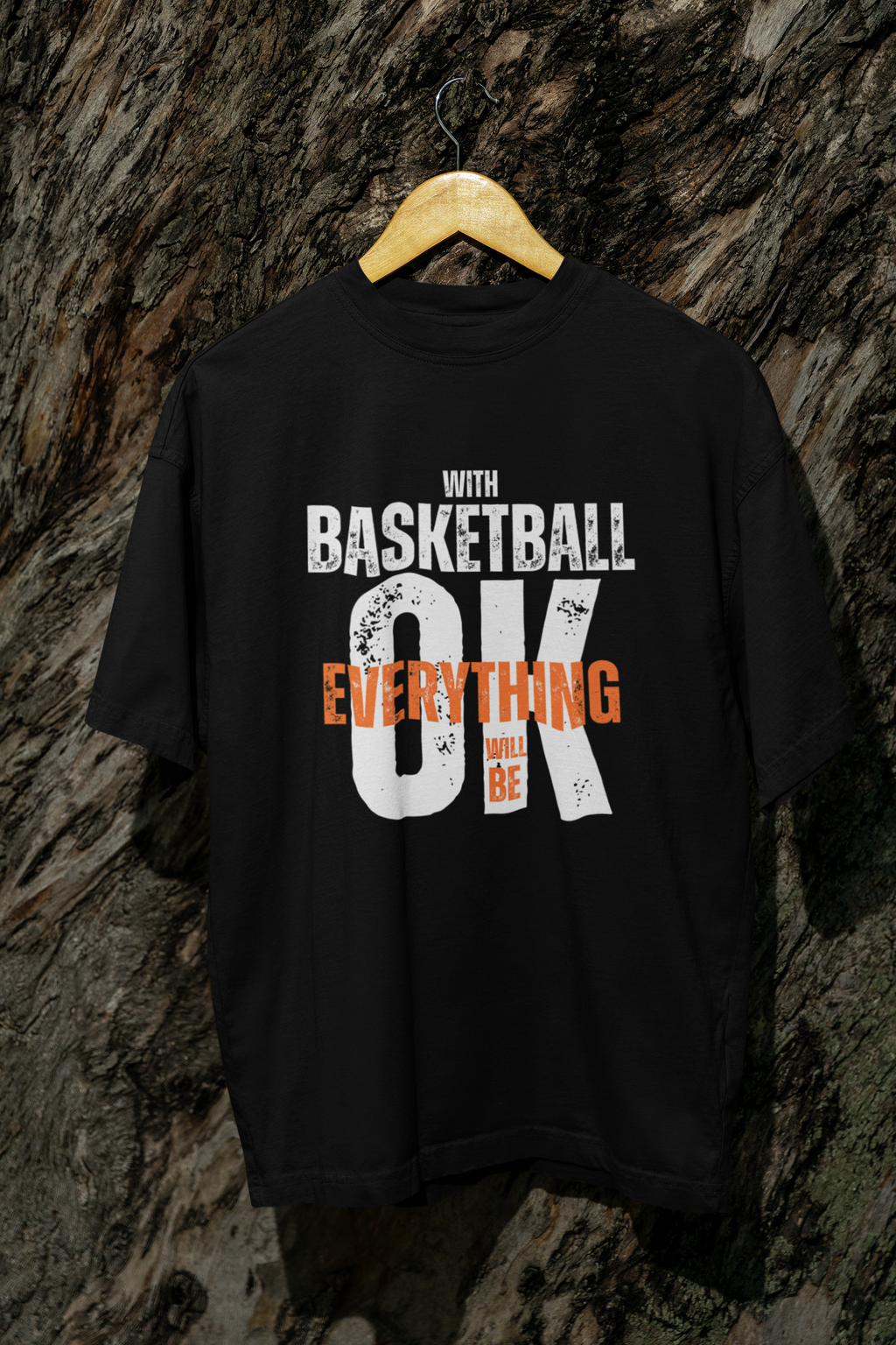 Mockup Schwarzes Oversized T-Shirt aus 100% Baumwolle mit dem Aufdruck "WITH BASKETBALL EVERYTHING WILL BE OK". Der Text ist in Weiß und Orange gehalten, wobei "EVERYTHING" und "WILL BE" in Orange hervorgehoben sind.