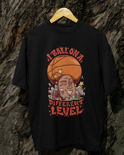 Mockup Schwarzes Oversized Basketball T-Shirt mit einem bunten Cartoon-Print einer zwinkernden Figur, die einen Basketball als Kopf hat. Der rote Text lautet „I BALL ON A DIFFERENT LEVEL“. 100% Baumwolle