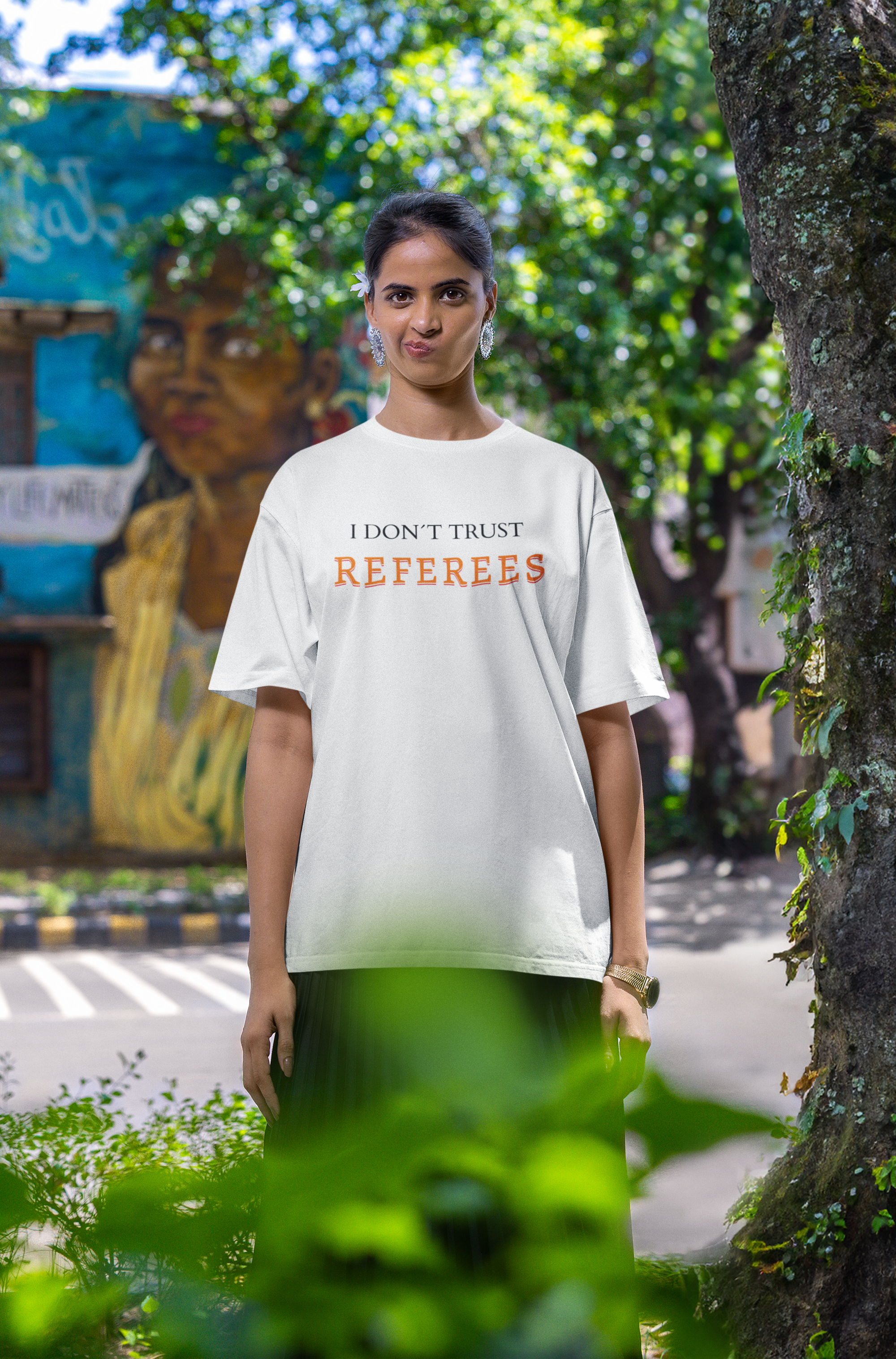 Mockup mit Model Weißes Oversized T-Shirt mit dem minimalistischen Statement-Print „I DON'T TRUST REFEREES“, wobei das Wort „REFEREES“ in Orange hervorgehoben ist. 100% Baumwolle.