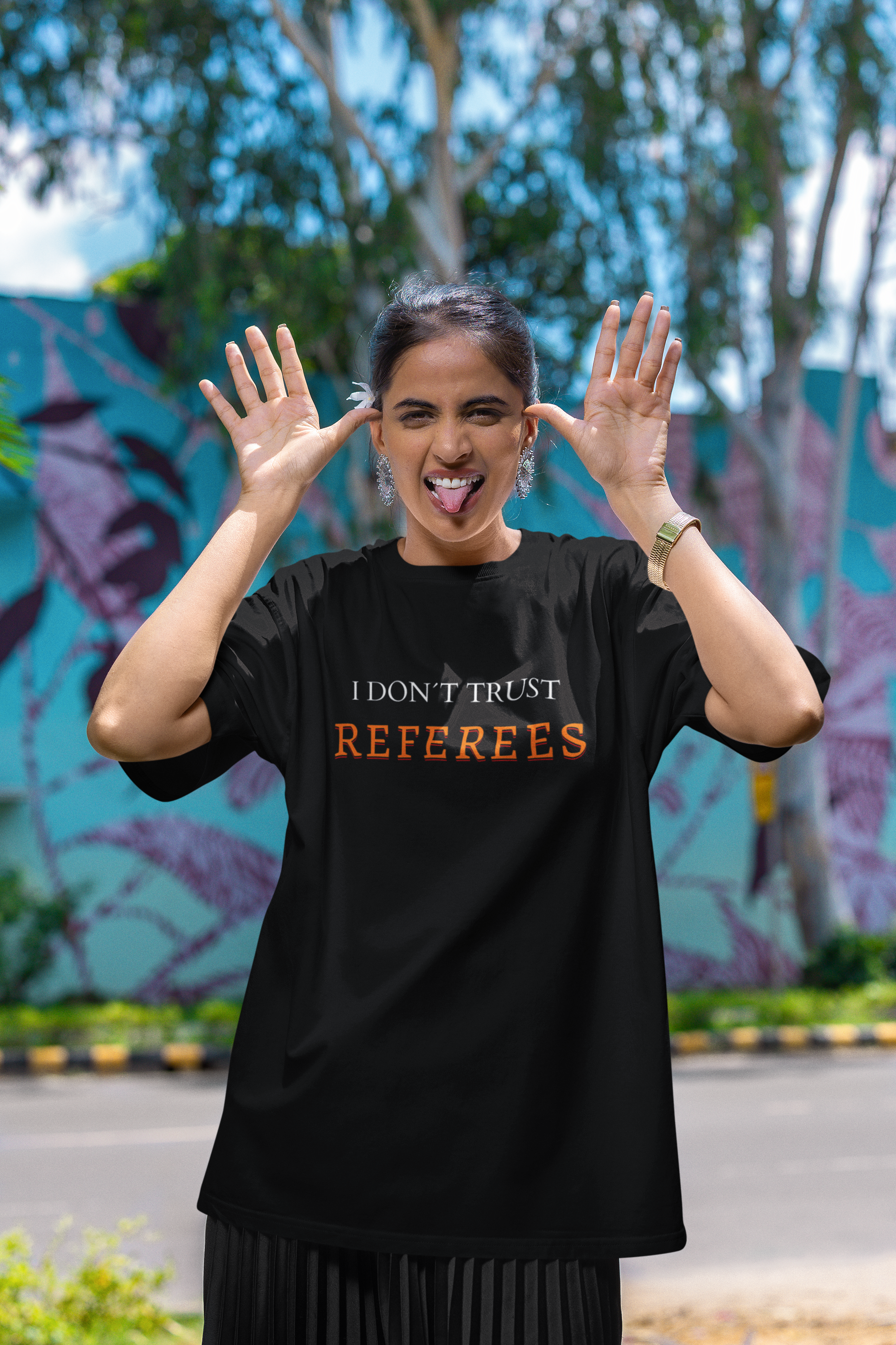 Mockup mit Model Schwarzes Oversized T-Shirt mit dem minimalistischen Statement-Print „I DON'T TRUST REFEREES“, wobei das Wort „REFEREES“ in Orange hervorgehoben ist. 100% Baumwolle.