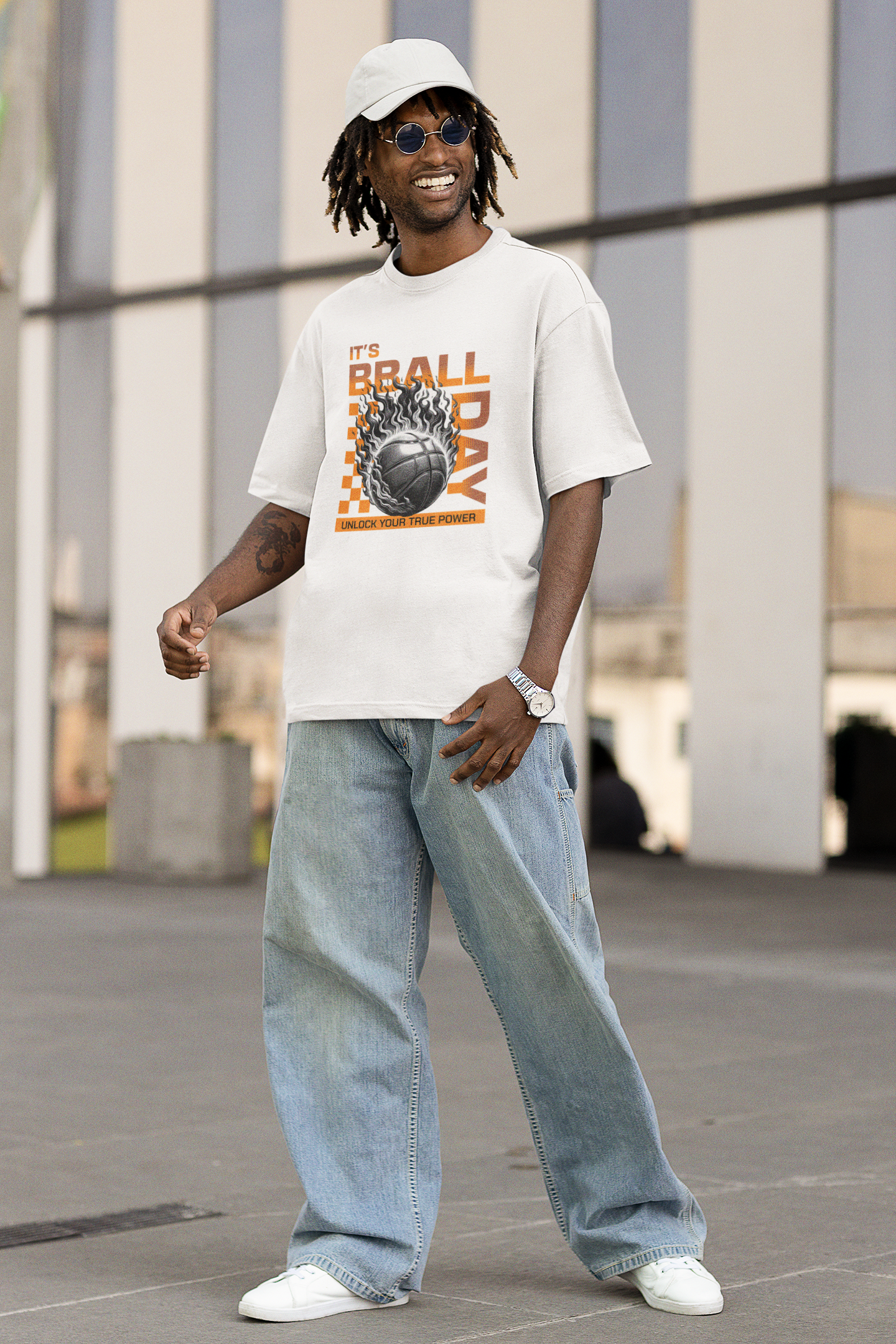 Mock mit Model Weißes Oversized T-Shirt mit einem Print eines brennenden Basketballs (Ball on Fire) und dem orangefarbenen Text „IT'S BBALL DAY“ und „UNLOCK YOUR TRUE POWER“. 100% Baumwolle.