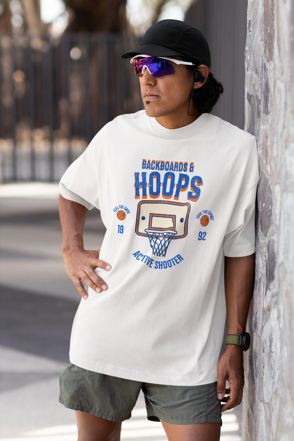 Mockup mit Model Weißes Oversized T-Shirt mit Retro-Print eines Basketballkorbs, dem Text „BACKBOARDS & HOOPS“ und dem Geburtsjahr „19 92“ in Orange und Blau. 100% Baumwolle
