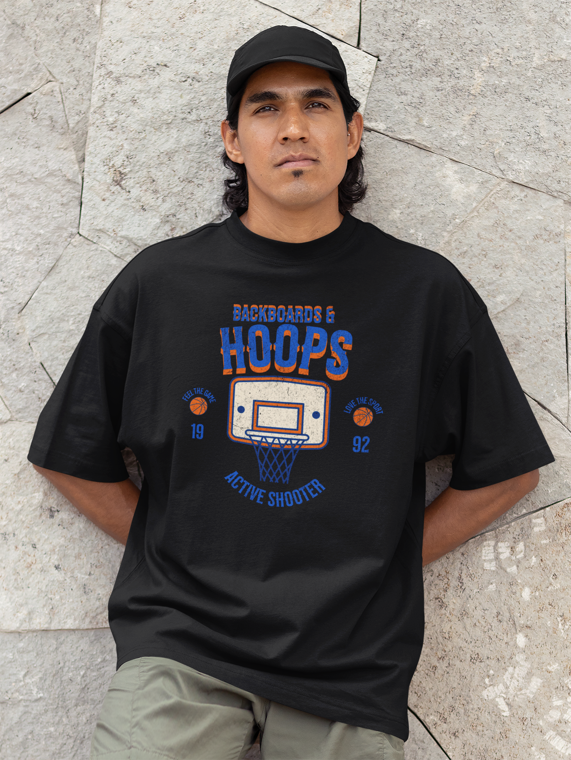 Mockup mit Model Schwarzes Oversized T-Shirt mit Retro-Print eines Basketballkorbs, dem Text „BACKBOARDS & HOOPS“ und dem Geburtsjahr „19 92“ in Orange und Blau. 100% Baumwolle