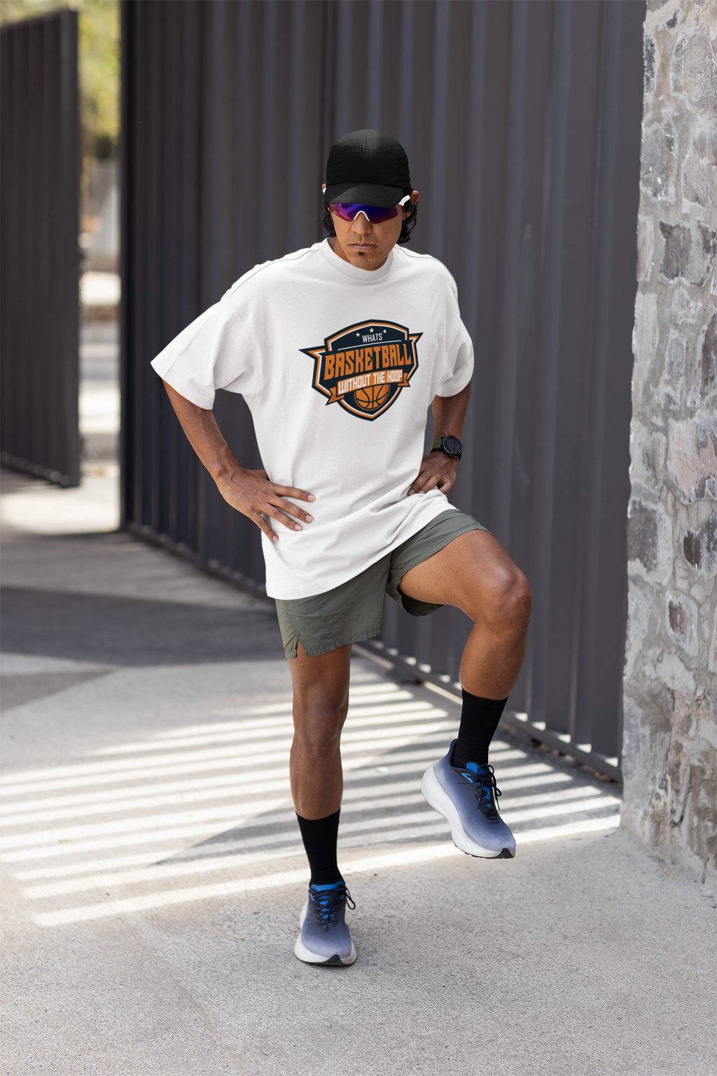 Mockup mit Model Weißes Oversized T-Shirt mit einem Basketball-Logo im Wappen-Stil in Orange, Weiß und Blau und dem Slogan "WHAT'S BASKETBALL WITHOUT THE HOOP". 100% Baumwolle.