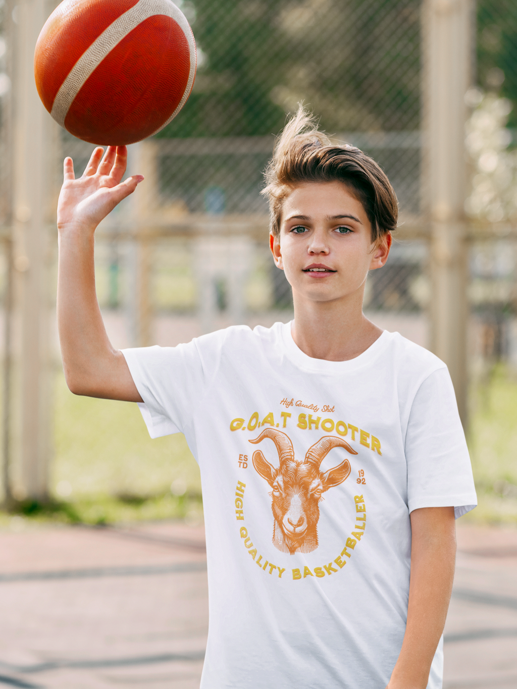 Mockup mit Weißen Oversized T-Shirt mit einem großen, orangefarbenen Print eines Ziegenkopfs (G.O.A.T.) und dem Text „G.O.A.T. SHOOTER“ und „HIGH QUALITY BASKETBALLER“. 100% Baumwolle.